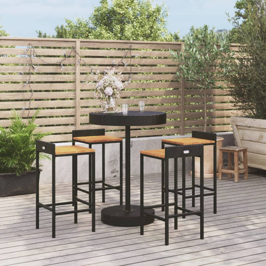 Rattan en acacia bistroset voor tuin met een ronde, zwarte, gevlochten tafel en vier hoge stoelen met houten zitvlakken, tegen de achtergrond van een houten schutting en terras.